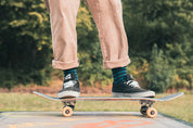 Person skateboarding outdoors wear green stripey socks with a blurred green background