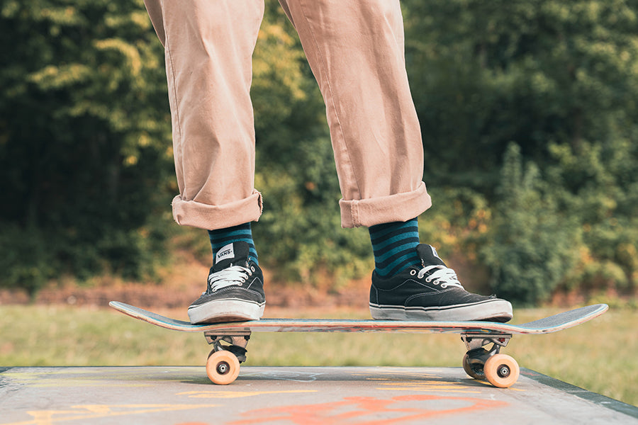 Person skateboarding outdoors wear green stripey socks with a blurred green background