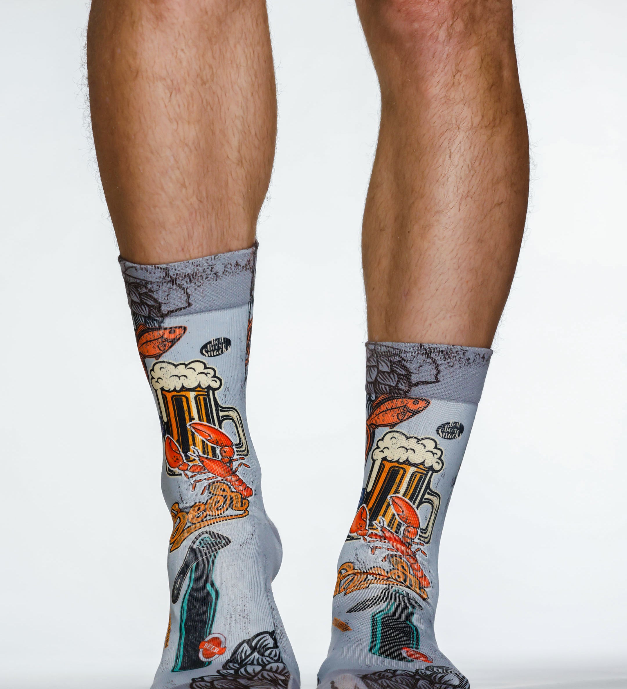 Gray socks with beer-themed design worn by a person on a white background