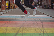 Person wearing red spotty socks and  jumping on a colorful crosswalk with blurred background