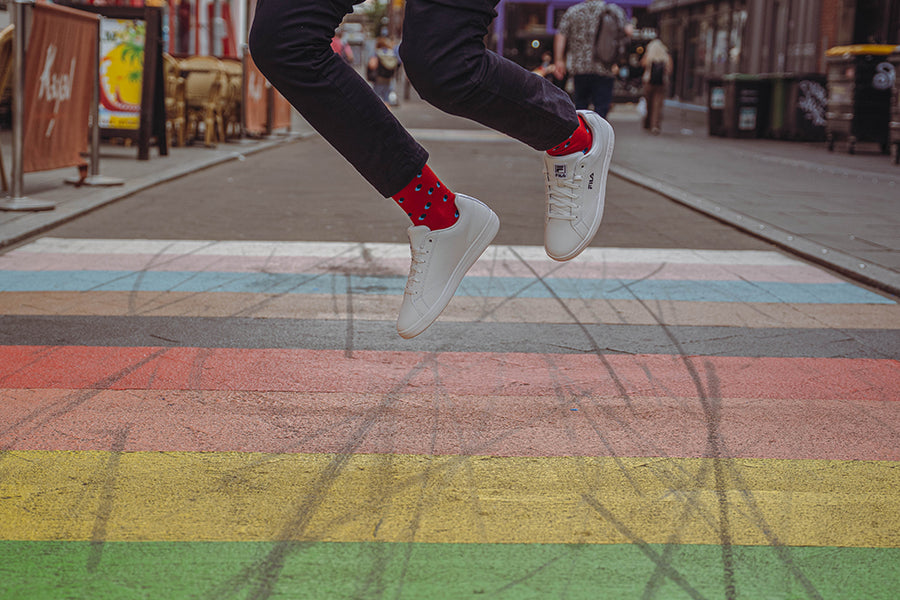 Person wearing red spotty socks and  jumping on a colorful crosswalk with blurred background