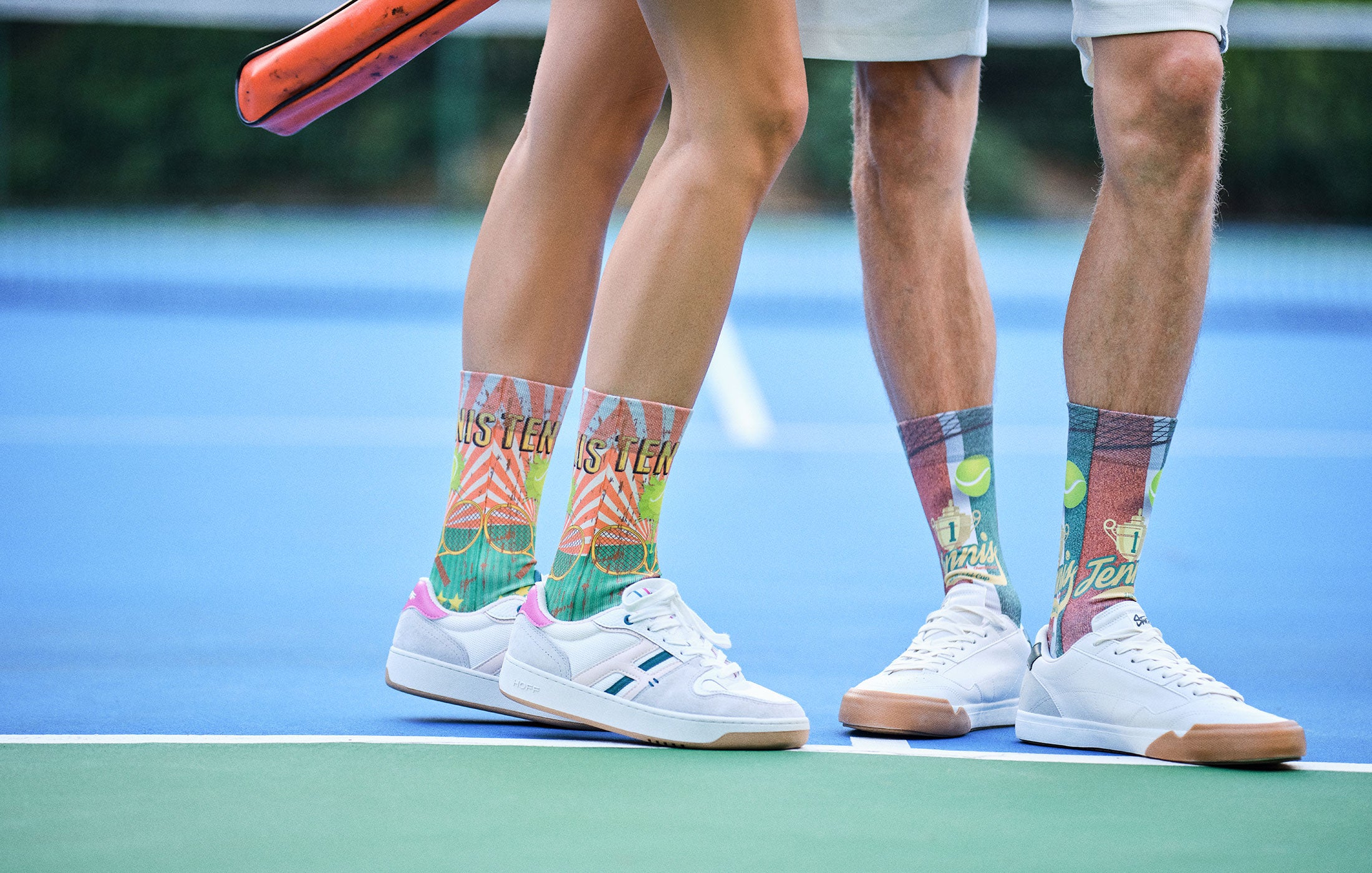 Tennis players on a court wearing colorful socks with brand names.