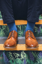 Person wearing brown leather shoes and blue socks on a decorative step.
