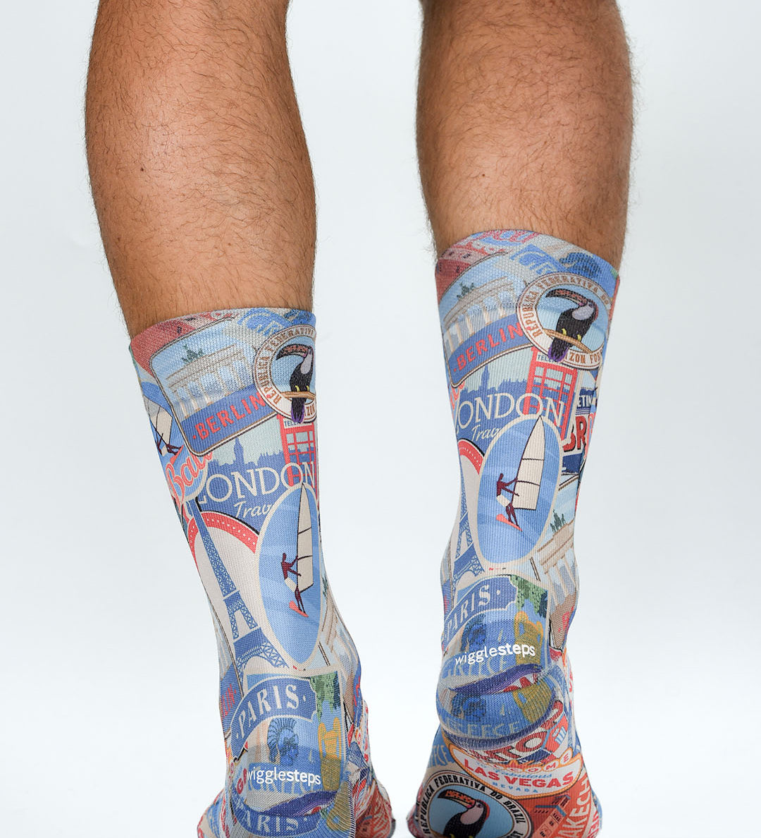 Colorful travel-themed socks with landmarks worn by a person on a white background