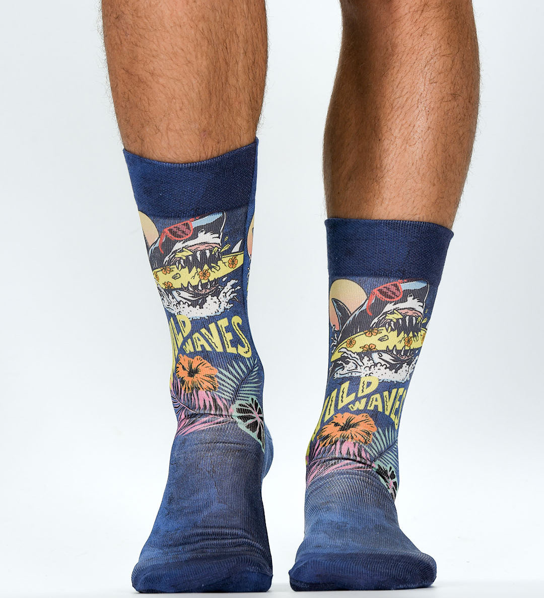 Colorful socks with shark design and 'WIld Waves' text worn by a person on a white background