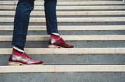 Person wearing maroon shoes and colourful stripe socks walking up a set of stairs.