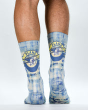 Blue and white patterned socks with airplane design worn by a person on a light gray background