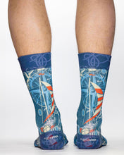 Blue socks with sailboat design worn by a person on a white background