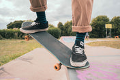 Person on a skateboard wearing green and black stripe socks with a park background
