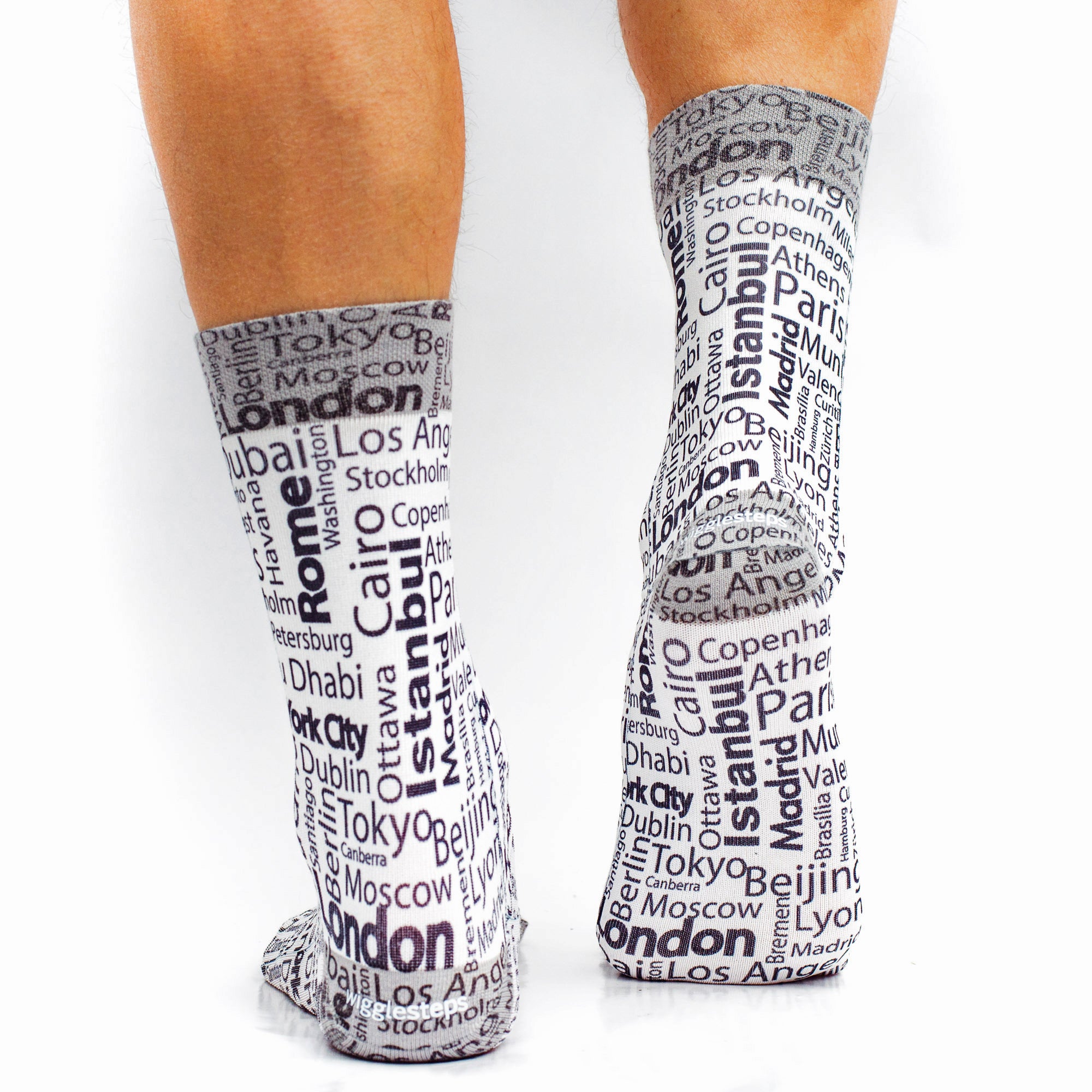 Gray socks with city names printed on them worn by a person.