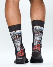 Black socks with fishing and beer-themed designs worn by a person on a white background