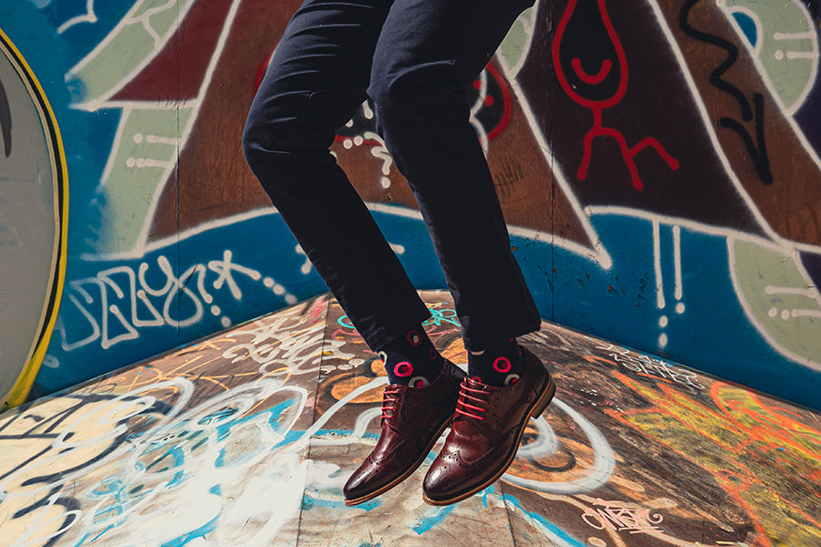 organic cotton spot design socks with formal shoes jumping over graffiti landscape