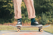 Person skateboarding outdoors wear green stripey socks with a blurred green background