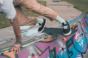 Person skateboarding on a graffiti-covered ledge wearing mint green socks