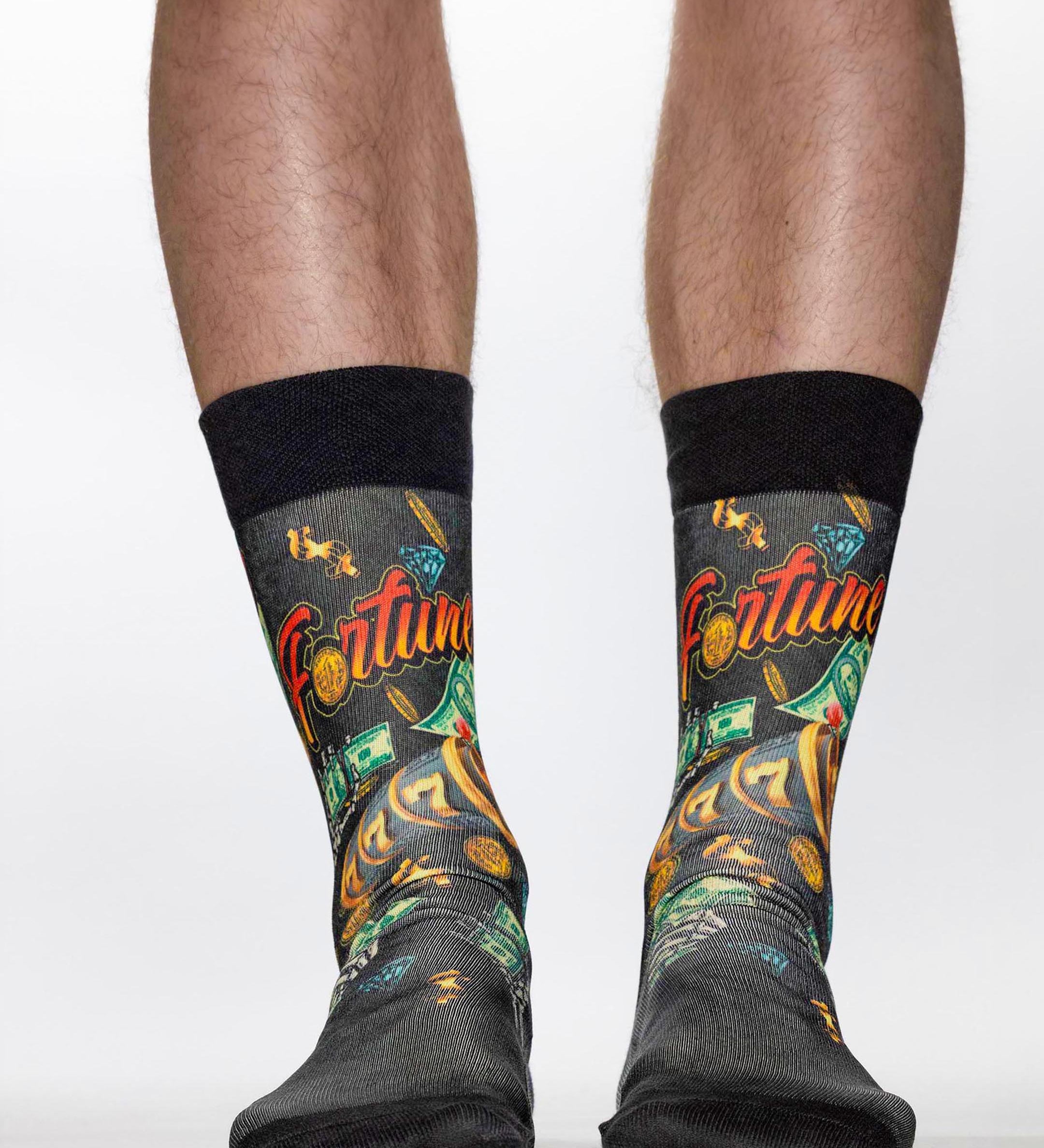 Black socks with colorful designs and 'Fortune' text worn by a person on a white background