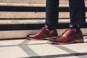 Brown leather shoes with spot detail socks and navy chinos on a person standing on steps.