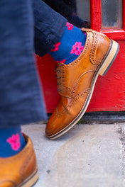 Brown leather shoes and blue socks with pink floral patterns on a red door background