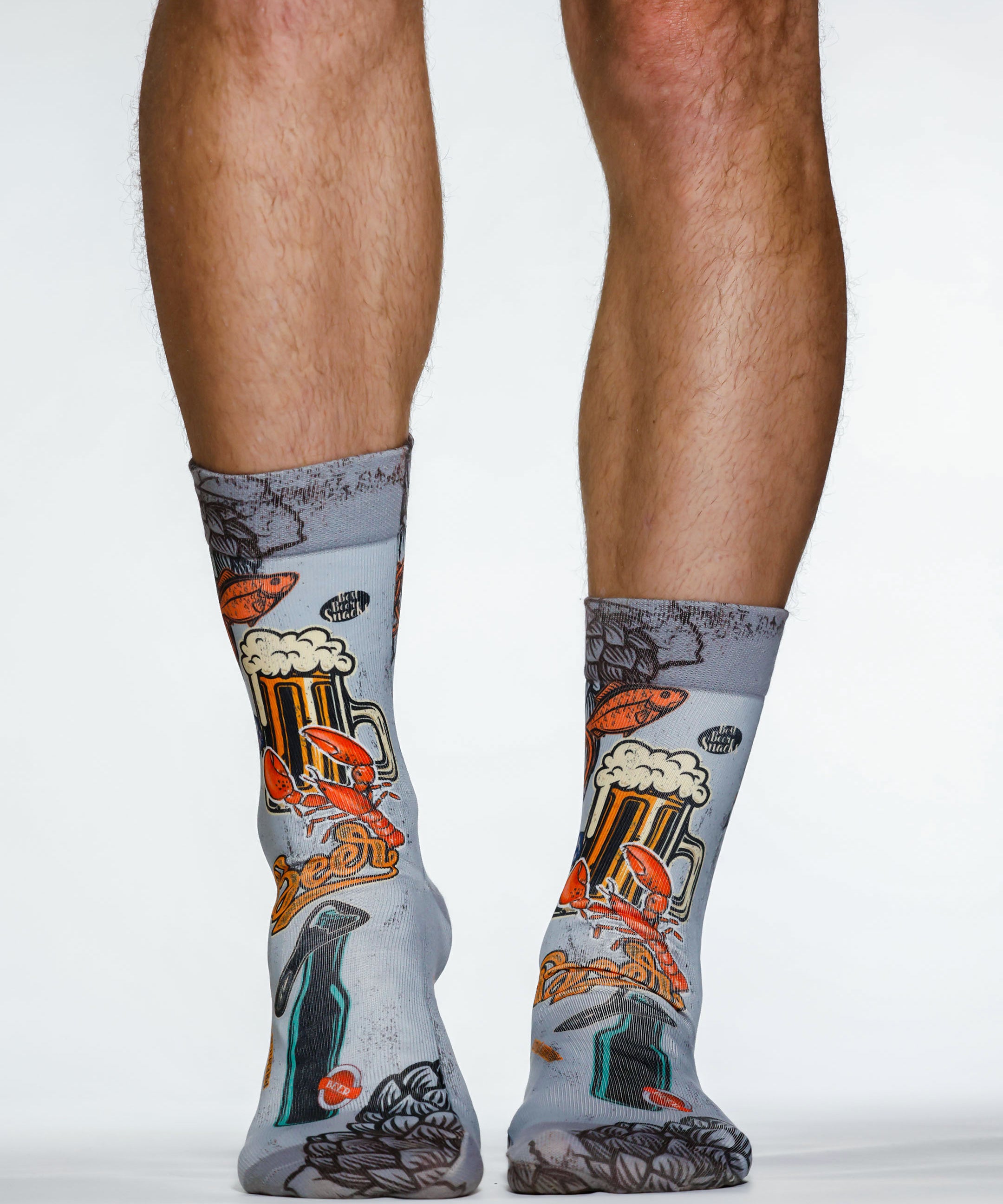 Gray socks with beer-themed design worn by a person on a white background