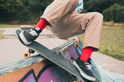 Person skateboarding on a rail wearing red socks with a blurred background