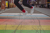 Person wearing red spotty socks and  jumping on a colorful crosswalk with blurred background