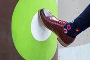 Person wearing red brogue shoes with spot design cotton socks
