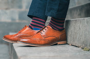 Brown leather shoes and striped socks on a concrete step
