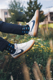blue polka dot socks mens feet in the air over grass landscape