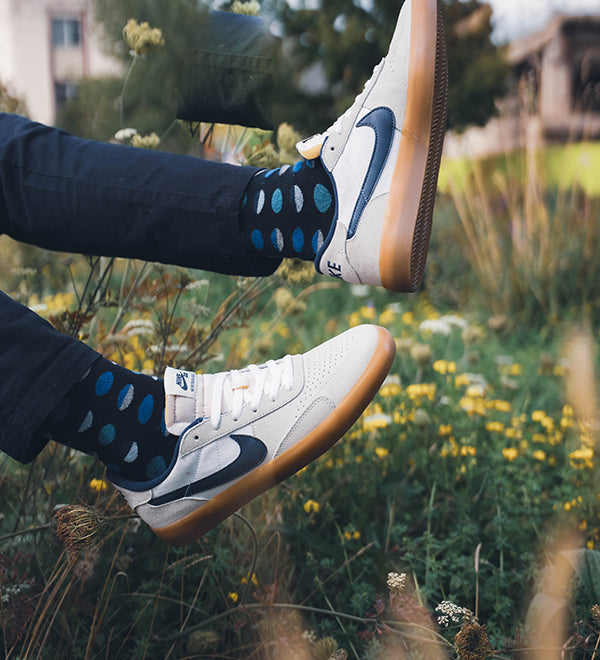 blue polka dot socks mens feet in the air over grass landscape