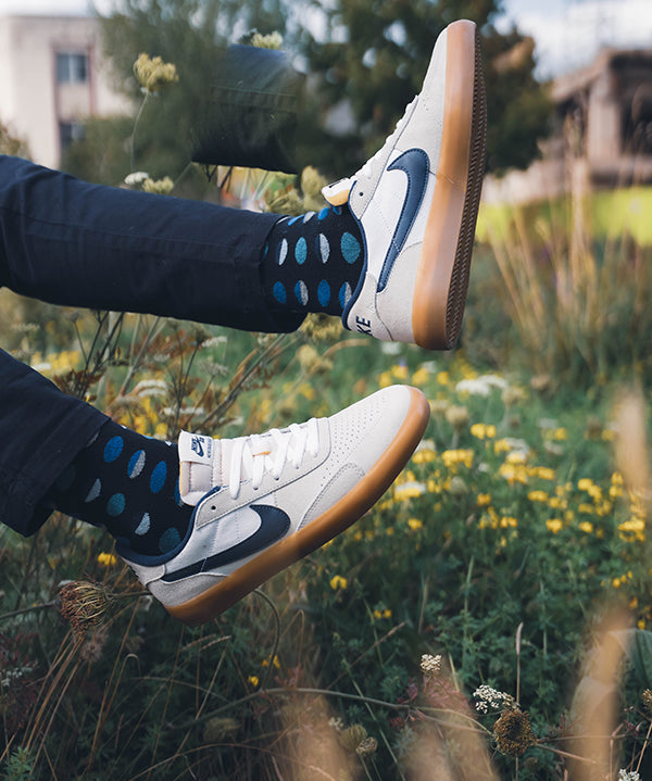 blue polka dot socks mens feet in the air over grass landscape