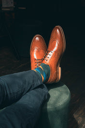 Brown leather shoes with blue socks on a dark background