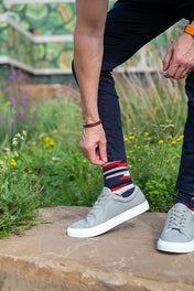 Person wearing gray sneakers and colorful socks standing on a stone surface with a natural background.