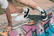 Person skateboarding on a graffiti-covered ledge wearing mint green socks