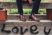 Dark Red Brogue Shoes with Navy Socks sat on wooden bench