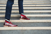 Person wearing maroon shoes and colourful stripe socks walking up a set of stairs.