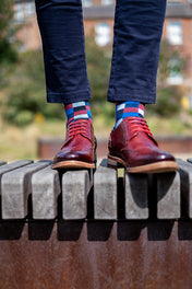 Person wearing red shoes and colorful socks standing on a metal railing with a blurred background