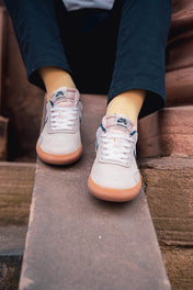 Yellow Socks and White sneakers with brown soles worn by a person sitting on steps.